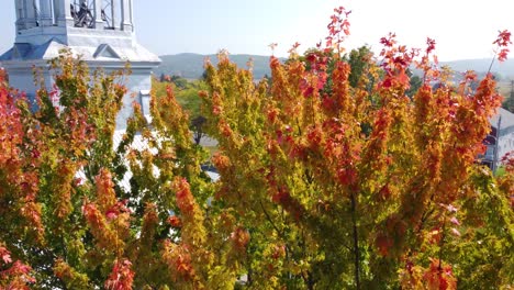 Rotierende-Aufnahme-Wunderschöner-Bunter-Bäume-Auf-Einem-Herbstlichen-Hintergrund-Neben-Einer-Kirche-An-Einem-Hellen,-Sonnigen-Tag
