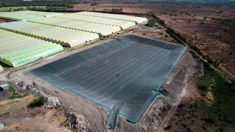 Landarbeiter-Im-Leeren-Bewässerungsbecken-Mit-Teichauskleidung-Auf-Einer-Gewächshausfarm-In-Kenia