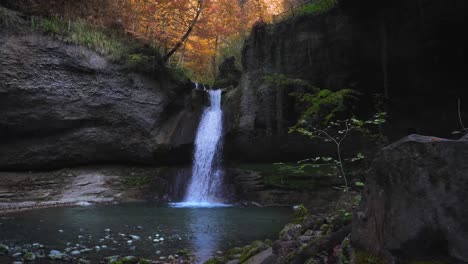 Water-falls-down-corner-of-rocky-ledge-in-Kemptner-Tobel-forest,-Autumn-foliage-in-Wetzikon-Switzerland