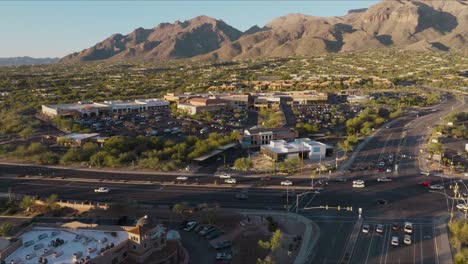 Luftdrohnenaufnahmen-Des-Belebten-Tucson-Arizona-Plaza-Bei-Tag-Mit-Bergen-Im-Hintergrund-Und-Autos,-Die-Auf-Der-Straße-Fahren