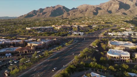 Aerial-Footage-of-Catalina-Foothills-Neighborhood-on-Golden-Sunny-Day,-Busy-Intersection-and-Shopping-Plaza-Below
