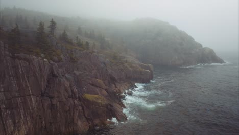 Fog-hangs-on-sparse-landscape-with-rocky-cliffs-descending-to-the-sea-far-below