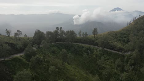 Highway-winds-around-mountain-across-valley-from-Mt-Bromo-volcano,-IDN