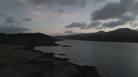 Dämmerung-über-Dunvegan-Castle-Auf-Der-Isle-Of-Skye-Mit-Ruhigem-Seewasser-Und-Sanften-Hügeln-Im-Hintergrund