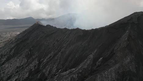 Aerial-flyover,-misty-smoky-volcano-crater-on-Mt-Bromo,-Java-Indonesia