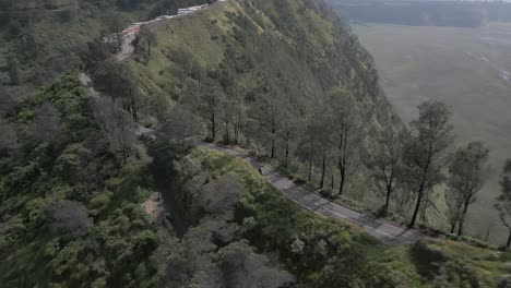 Flyover-of-narrow-mountain-ridge-scenic-highway,-valley-in-Java-IDN