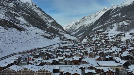 Tall-mountain-peaks-and-valley-in-Zermatt,-Switzerland-with-ski-resort-and-town-on-bright-winter-day