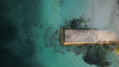 Flying-directly-above-Caravelle-Beach-and-concrete-jetty-in-Sainte-Anne,-Guadeloupe