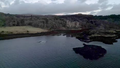 Dunvegan-castle-on-the-isle-of-skye,-surrounded-by-woodlands-and-coastal-waters-at-dusk,-aerial-view