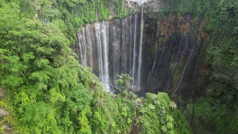 Aerial-descent-into-lush-jungle-canyon-at-Tumpak-Sewu-waterfall,-Java