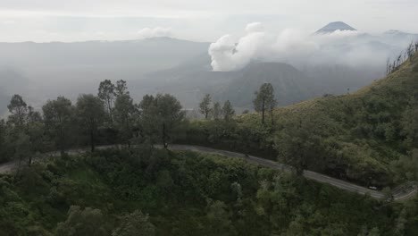Aerial-tracks-moto-on-high-mountain-road-opposite-volcano-on-Java