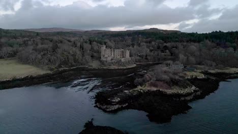 Dunvegan-castle-on-the-isle-of-skye-surrounded-by-woodland-and-water-at-dusk,-aerial-view