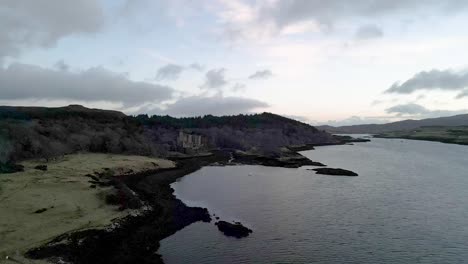 Dunvegan-castle-on-the-isle-of-skye,-surrounded-by-woodlands-and-water-at-dusk,-aerial-view