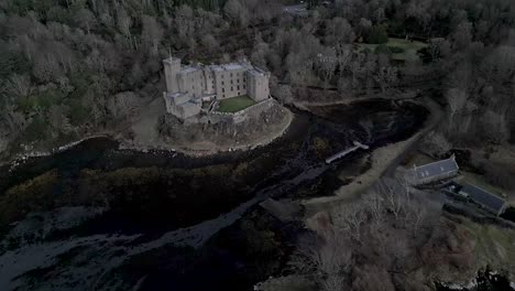 Dunvegan-castle-on-the-isle-of-skye,-surrounded-by-woodlands-and-water,-under-overcast-skies,-aerial-view