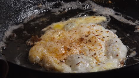 Closeup:-Crispy-fried-egg-removed-from-hot-buttery-pan-with-spatula