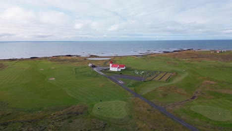Every-day-life-scene,-golfers-playing-on-golf-field-next-to-typical-scenic-church,-Iceland