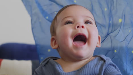 Baby-Lächelt-Und-Lacht-Und-Spielt-In-Zeitlupe-Mit-Einer-Blauen-Seide-Mit-Gelben-Sternen