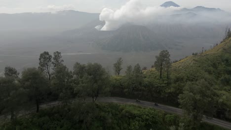 Volcano-in-distance-as-motorcycles-ride-on-twisted-mountain-road