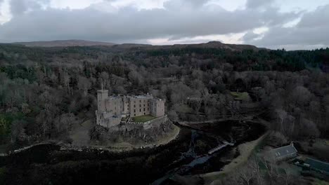 Dunvegan-castle-on-isle-of-skye-surrounded-by-woodland-in-overcast-weather,-aerial-view