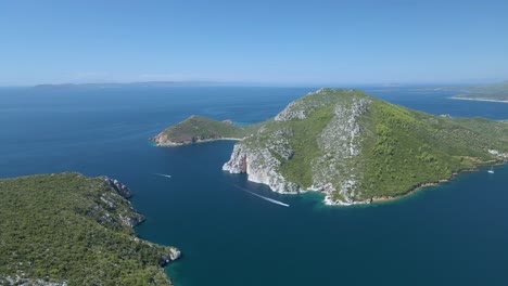Cinematic-rotating-up-high-4K-drone-clip-over-the-tropical-blue-waters-of-Toroni-in-Chalkidiki-with-some-boats-passing-by