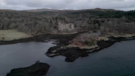 Dunvegan-castle-on-the-isle-of-skye,-surrounded-by-woodlands-and-coastal-waters,-under-a-cloudy-sky,-aerial-view