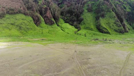 Aerial-approaches-bright-green-ash-slope-inside-volcano-caldera,-moto