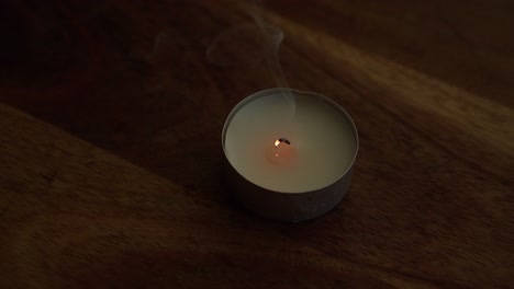 Wick-of-tea-light-smokes-after-candle-is-blown-out,-close-up-view