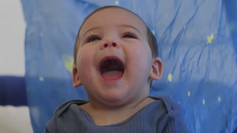 Baby-smiling-and-laughing-playing-with-a-blue-silk-with-yellow-stars-in-slow-motion