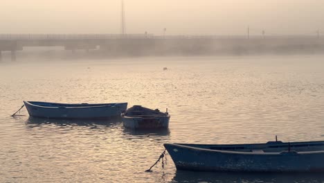 Fishing-boats-gracefully-float-upon-the-water's-surface,-embraced-by-the-ethereal-embrace-of-mist-and-fog,-fashioning-a-serene-maritime-atmosphere