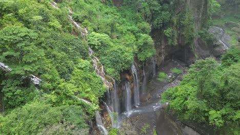 Aerial-descends-into-deep-misty-lush-waterfall-canyon-on-Java,-IDN