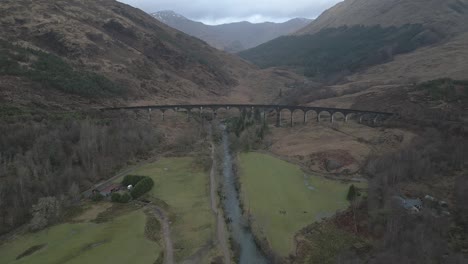 Glenfinnan-viaduct-in-scotland-with-surrounding-landscape,-overcast-weather,-aerial-view
