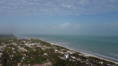 El-cuyo,-a-serene-beach-town-in-mexico-with-clear-skies-and-lush-greenery,-aerial-view
