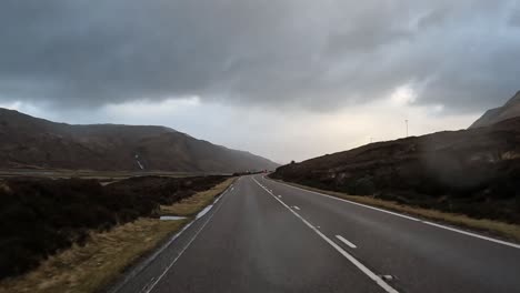 Open-road-in-Scotland's-Isle-of-Skye-with-overcast-skies-and-rolling-hills,-shot-in-a-moving-vehicle