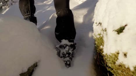 Woman-hiking-snowy-hill-with-snow-chains-and-gaiters-on-shoes,-handheld-slow-motion