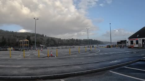 Empty-ferry-terminal-on-Skye-Island,-Scotland-with-marked-lanes,-yellow-bollards-under-a-cloudy-sky,-daylight