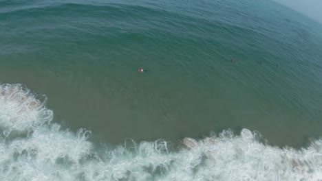 Rundblick-Aus-Der-Luft-über-Die-Meereslandschaft-Mit-Menschen,-Die-In-Den-Wellen-Schwimmen