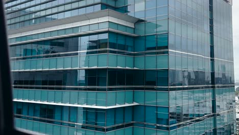 POV-Einer-Person,-Die-Mit-Der-Seilbahn-Fährt-–-Glasfassade-Eines-Modernen-Firmengebäudes-In-Singapur
