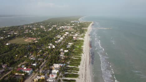 El-cuyo-beach-town-in-mexico,-showcasing-coastal-houses-and-lush-greenery,-aerial-view