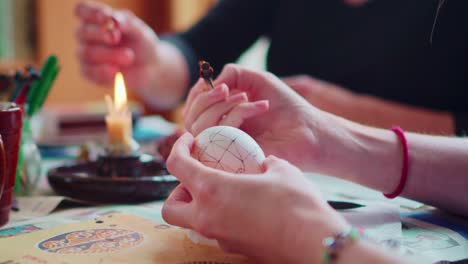 Closeup-on-Artists-Hands-Drawing-Traditional-Ornate-Designs-on-Easter-Eggs-with-Stylus