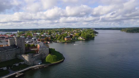 Drone-shot-flying-parallel-to-a-boat-behind-the-Vaxholm-Fortress-in-Sweden-near-Stockholm