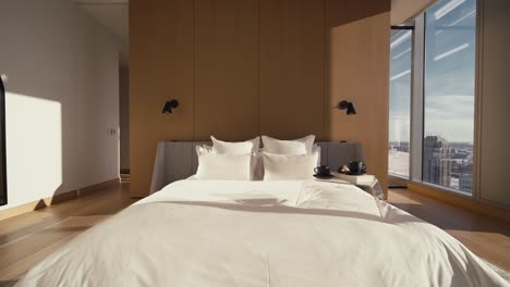 Ein-Großes-Weißes-Bett-In-Einem-Luxuriösen-Schlafzimmer-Mit-Großen-Fenstern,-Die-Natürliches-Sonnenlicht-Hereinlassen