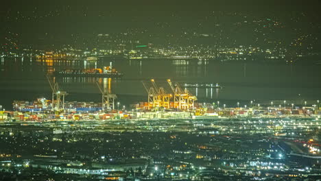 High-angle-night-timelapse-over-illuminated-Oakland-Port-with-traffic-flow
