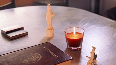 Close-up-4K-video-of-the-Holy-Bible-book-with-statue-of-the-Holy-Mary-and-candle-light-next-to-it