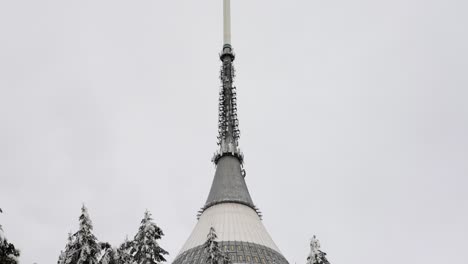 Reveal-of-tall-television-transmitter-tower-on-mountain-top-in-snowy-winter