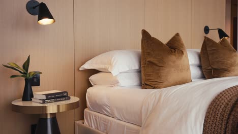 tight-shot-of-a-neatly-made-bed-with-a-bedside-lamp-and-table-in-the-bedroom-of-a-home