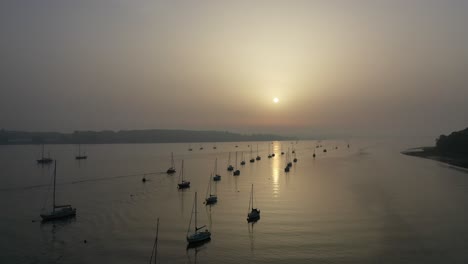 stationary-aerial-footage-with-yacht-moving-through-the-channel-using-an-engine,-at-sunrise
