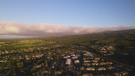 Panoramic-aerial-establishing-view-of-neighborhood-below-toe-slope-of-tropical-island-with-grey-cloud-band