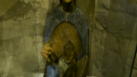 Pequeña-Muñeca-Religiosa-Sostiene-La-Figura-Del-Niño-Cristo-Detrás-De-Una-Vitrina