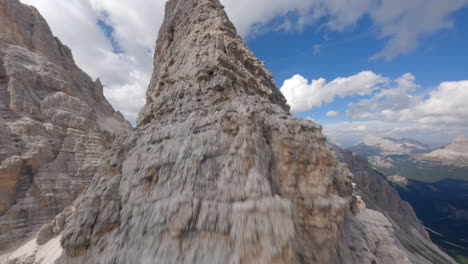 FPV-drone-rising-sharp-edge-of-rocky-Dolomites-mountain-range-in-Italy