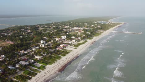 El-cuyo,-a-tranquil-beach-town-in-mexico,-with-lush-greenery-and-serene-beaches,-under-clear-skies,-aerial-view